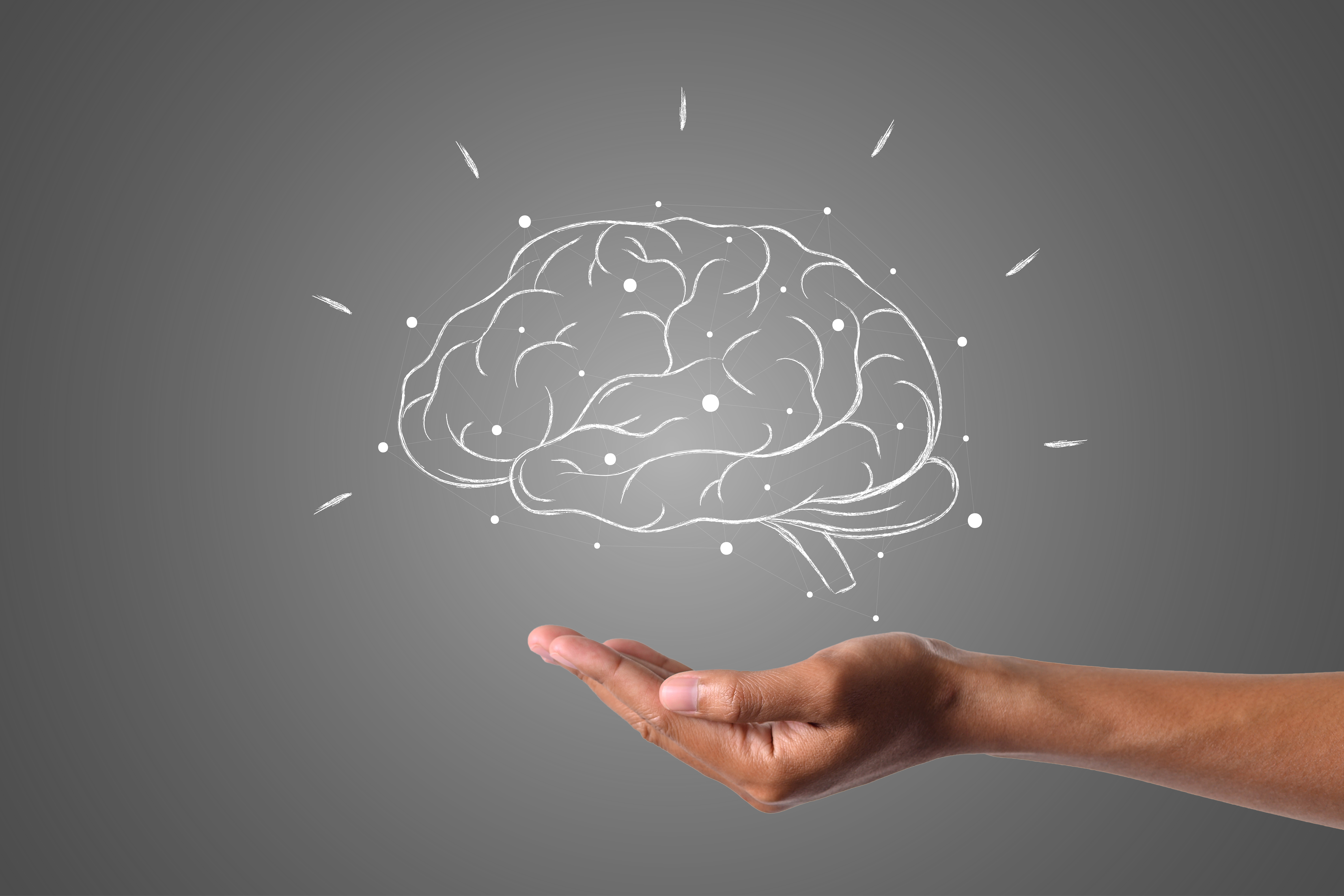 Main tendue soutenant une illustration num&eacute;rique d&rsquo;un cerveau sur fond gris fonc&eacute;, repr&eacute;sentant la puissance mentale, la concentration et la performance cognitive dans le cadre du je&ucirc;ne intermittent et du biohacking