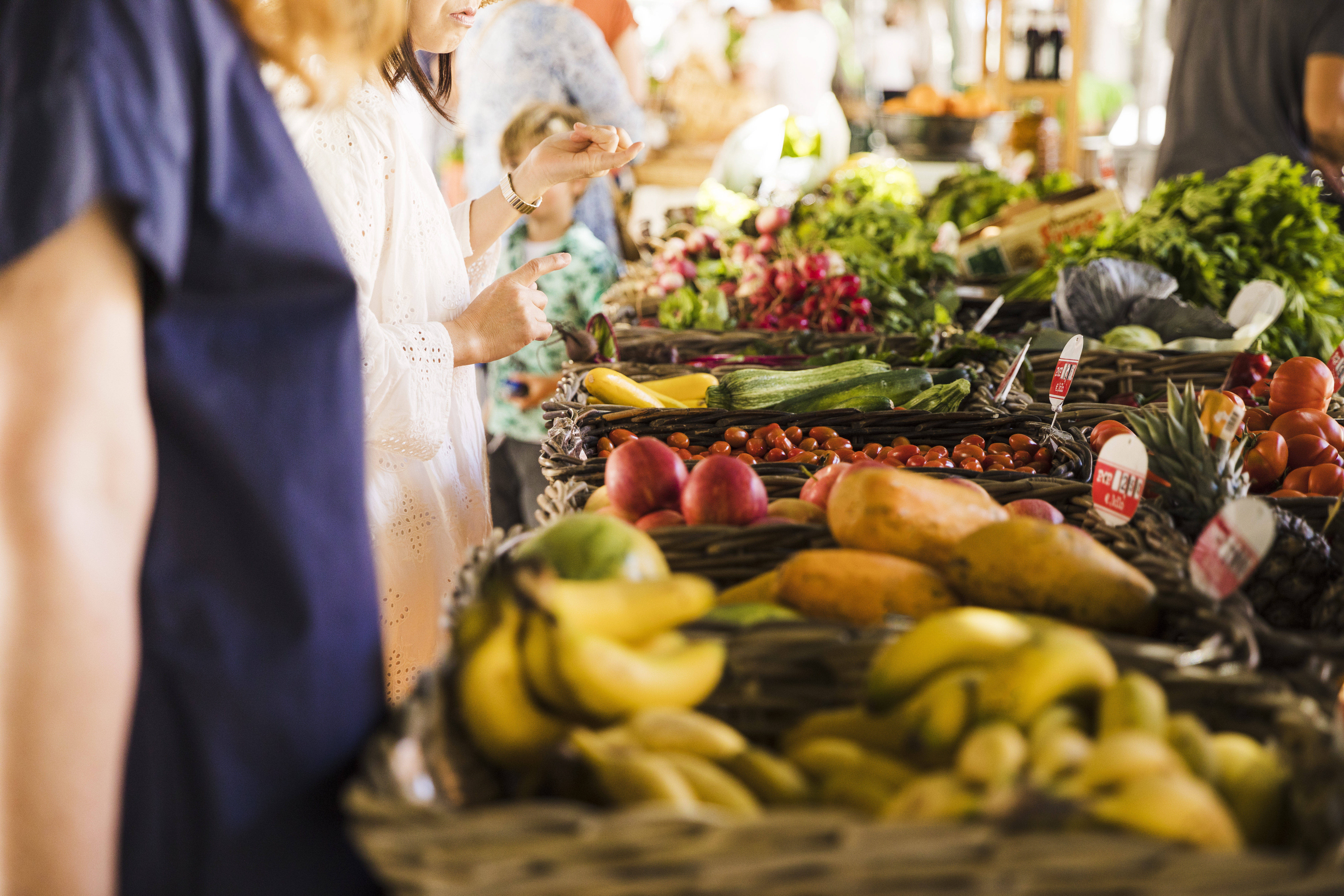 Personas eligiendo frutas y verduras en un mercado local, promoviendo consumo responsable y productos sostenibles